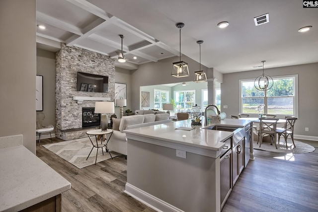 793 Oak Valley Dr, Blythewood, SC 29016 - kitchen with a fireplace, beam ceiling, dark wood-style floors, decorative light fixtures, and an island with sink