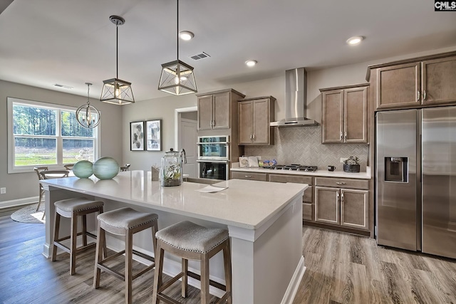 793 Oak Valley Dr, Blythewood, SC 29016 - kitchen featuring appliances with stainless steel finishes, wall chimney range hood, wood finished floors, light countertops, and a kitchen breakfast bar