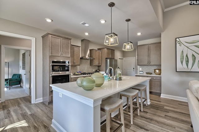 793 Oak Valley Dr, Blythewood, SC 29016 - kitchen with wall chimney exhaust hood, appliances with stainless steel finishes, a breakfast bar, tasteful backsplash, and wood finished floors