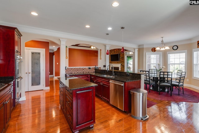 340 Heritage Forest Dr, Blythewood, SC 29045 - kitchen with appliances with stainless steel finishes, dark brown cabinets, arched walkways, wood finished floors, and ornate columns