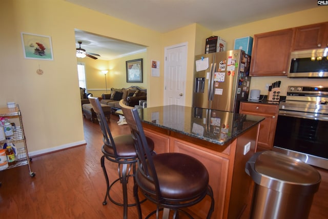 458 Laurel Mist Ln, West Columbia, SC 29170 - kitchen with appliances with stainless steel finishes, wood finished floors, a kitchen bar, a ceiling fan, and dark stone countertops
