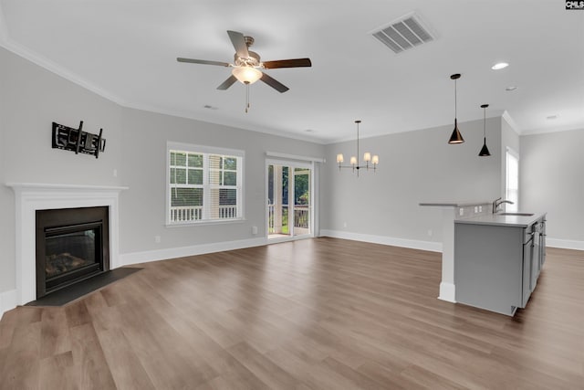 386 Amalfi Dr, Chapin, SC 29036 - unfurnished living room featuring a chandelier, a ceiling fan, crown molding, a fireplace with flush hearth, and light wood finished floors