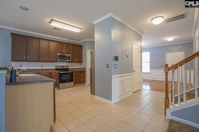 418 Abbeydale Way, Columbia, SC 29229 - kitchen with stainless steel appliances, light tile patterned flooring, crown molding, dark countertops, and wainscoting