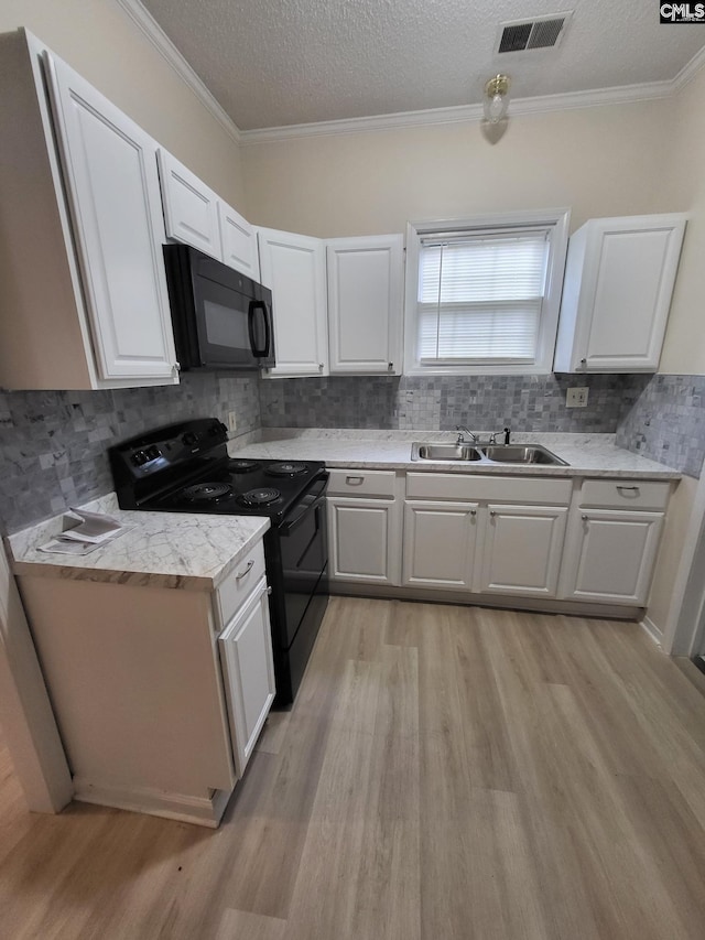 337 Mill St, Batesburg, SC 29006 - kitchen featuring black appliances, light wood-type flooring, white cabinets, tasteful backsplash, and crown molding