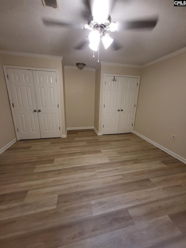 337 Mill St, Batesburg, SC 29006 - unfurnished bedroom featuring ornamental molding, wood finished floors, ceiling fan, a textured ceiling, and multiple closets