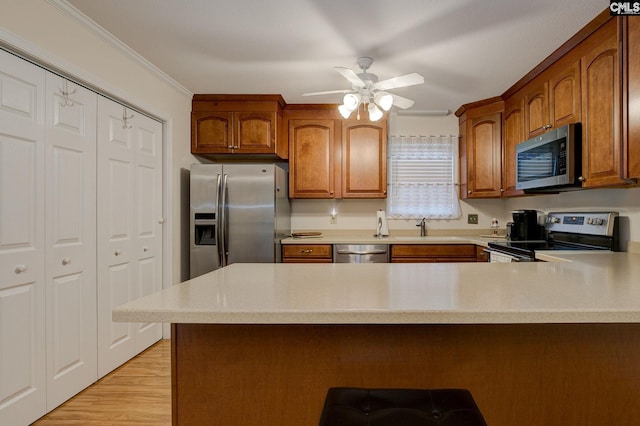 122 Halling Dr, Columbia, SC 29229 - kitchen featuring appliances with stainless steel finishes, light countertops, a peninsula, brown cabinets, and ornamental molding