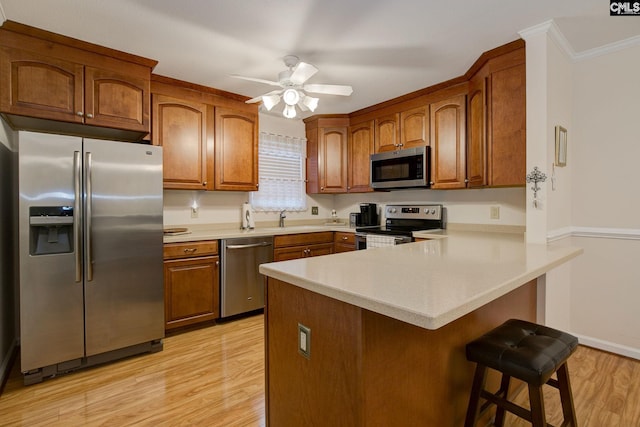 122 Halling Dr, Columbia, SC 29229 - kitchen featuring stainless steel appliances, light wood-style flooring, a peninsula, a breakfast bar area, and brown cabinets
