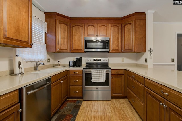 122 Halling Dr, Columbia, SC 29229 - kitchen featuring stainless steel appliances, brown cabinets, light countertops, light wood finished floors, and ornamental molding