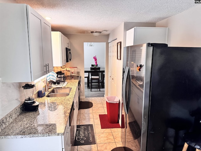 407 N Donar Dr, Columbia, SC 29229 - kitchen featuring freestanding refrigerator, black microwave, light stone countertops, a textured ceiling, and backsplash