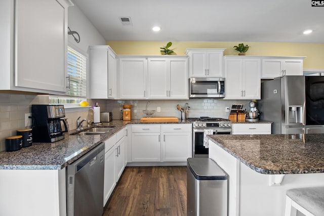 1420 Fair Forest Ln, Chapin, SC 29036 - kitchen with appliances with stainless steel finishes, white cabinets, dark wood-style floors, dark stone countertops, and decorative backsplash
