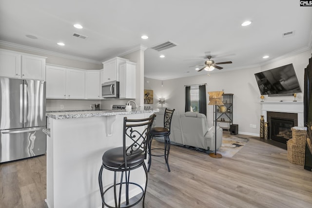 345 Wahoo Cir, Irmo, SC 29063 - kitchen with appliances with stainless steel finishes, open floor plan, white cabinetry, light stone counters, and ornamental molding