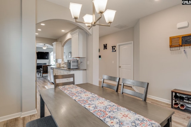 1013 Ashcroft Cir, Columbia, SC 29229 - dining area featuring arched walkways, light wood-type flooring, recessed lighting, ceiling fan, and a chandelier