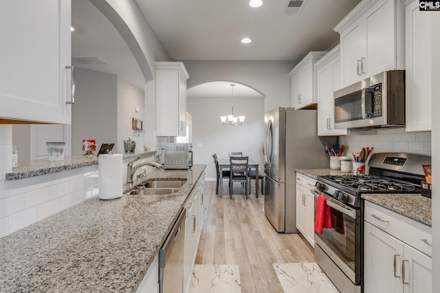 1013 Ashcroft Cir, Columbia, SC 29229 - kitchen featuring appliances with stainless steel finishes, arched walkways, white cabinetry, light wood-type flooring, and recessed lighting