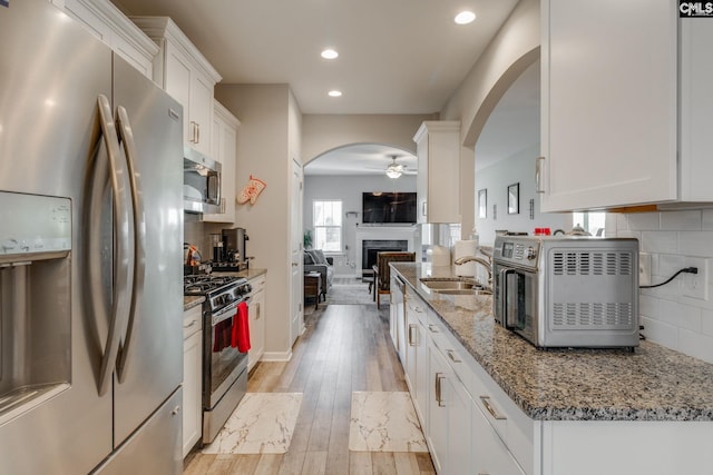 1013 Ashcroft Cir, Columbia, SC 29229 - kitchen with appliances with stainless steel finishes, arched walkways, a ceiling fan, a fireplace, and white cabinets