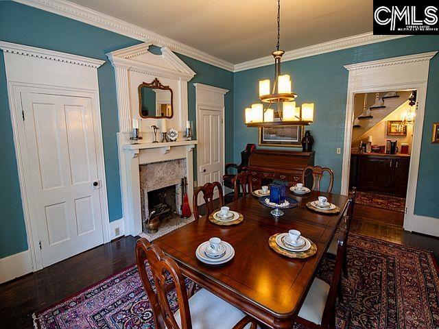 1220 Calhoun St, Newberry, SC 29108 - dining area featuring wood finished floors, crown molding, a fireplace, and a chandelier