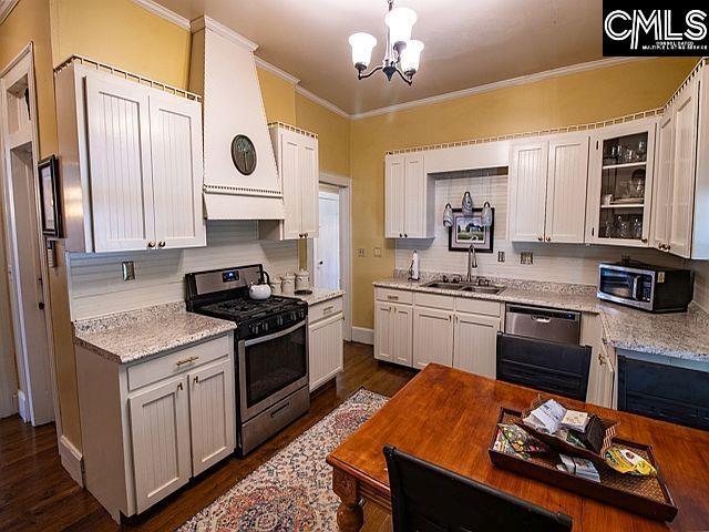 1220 Calhoun St, Newberry, SC 29108 - kitchen featuring stainless steel appliances, ornamental molding, a chandelier, dark wood-style floors, and glass insert cabinets