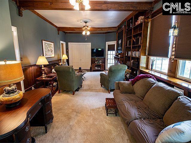 1220 Calhoun St, Newberry, SC 29108 - carpeted living area featuring healthy amount of natural light, ceiling fan, beamed ceiling, and crown molding