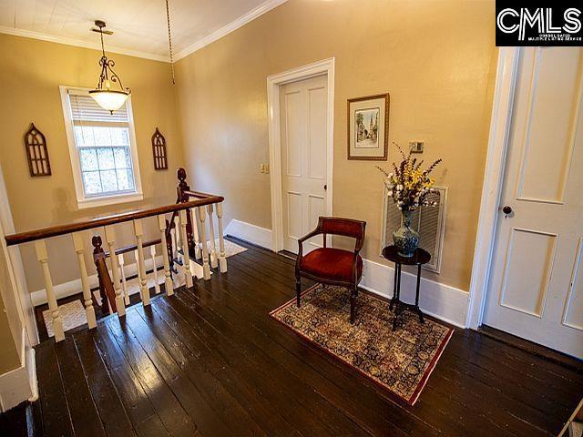 1220 Calhoun St, Newberry, SC 29108 - living area featuring wood-type flooring, an upstairs landing, and ornamental molding