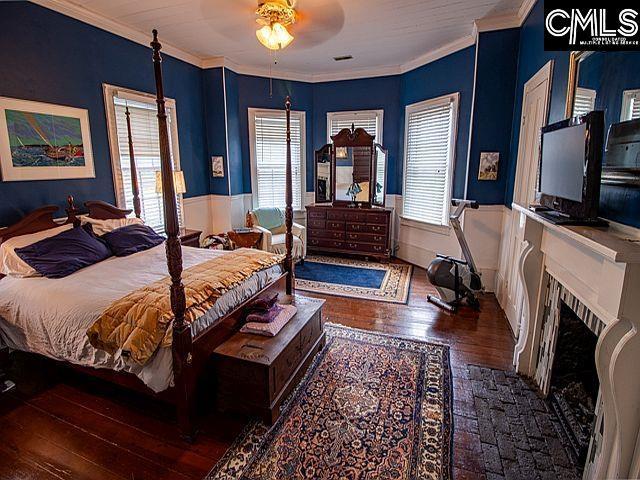 1220 Calhoun St, Newberry, SC 29108 - bedroom featuring wood-type flooring, crown molding, a fireplace with flush hearth, and wainscoting