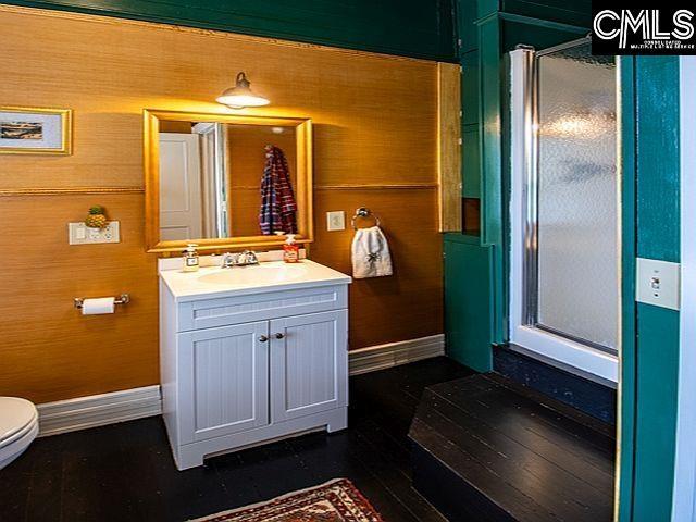 1220 Calhoun St, Newberry, SC 29108 - bathroom featuring vanity, a shower stall, wood finished floors, and wooden walls