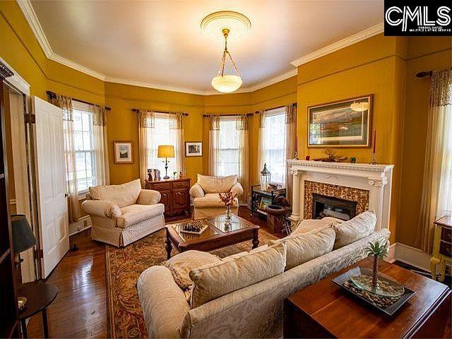 1220 Calhoun St, Newberry, SC 29108 - living room with ornamental molding, dark wood-style flooring, healthy amount of natural light, and a fireplace