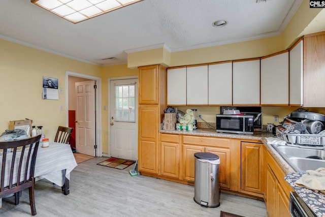2161 Tanglewood Rd, Sumter, SC 29154 - kitchen featuring stainless steel microwave, dishwashing machine, light wood-style flooring, crown molding, and light countertops