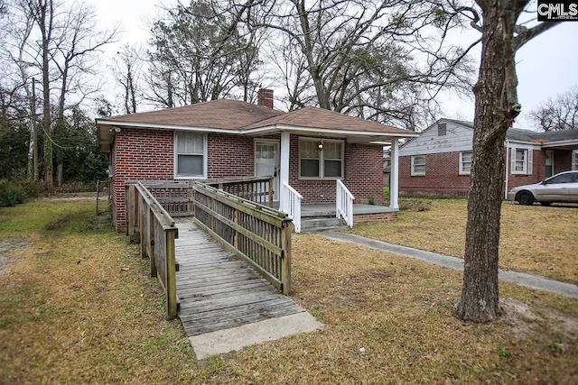 113 Brookland Cir, Columbia, SC 29204 - bungalow featuring a chimney, a front yard, brick siding, covered porch, and roof with shingles