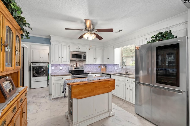 1220 Barnwell Dr, Sumter, SC 29154 - kitchen featuring appliances with stainless steel finishes, washer / clothes dryer, light marble finish floors, white cabinetry, and a kitchen island
