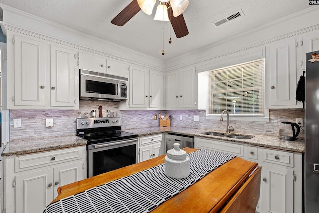 1220 Barnwell Dr, Sumter, SC 29154 - kitchen featuring appliances with stainless steel finishes, white cabinetry, backsplash, crown molding, and a textured ceiling