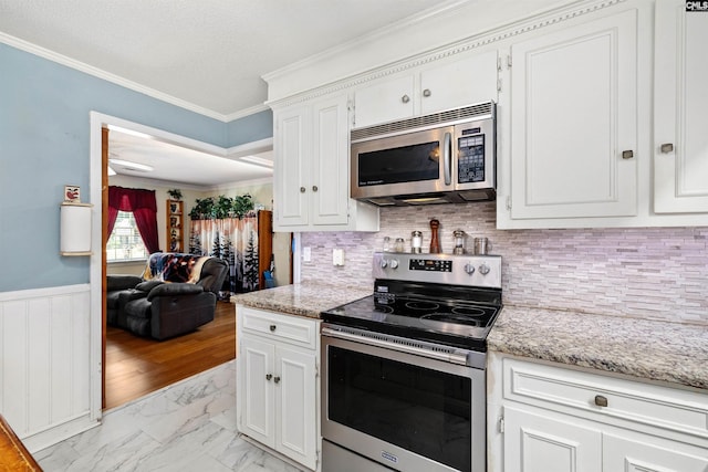 1220 Barnwell Dr, Sumter, SC 29154 - kitchen featuring appliances with stainless steel finishes, light marble finish flooring, ornamental molding, white cabinetry, and wainscoting