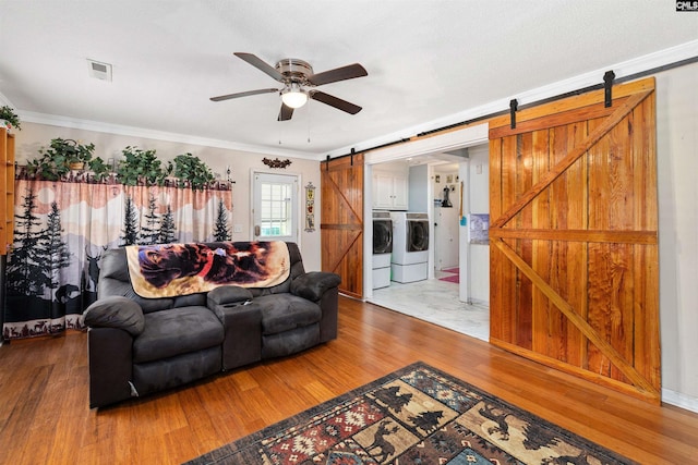 1220 Barnwell Dr, Sumter, SC 29154 - living room with a barn door, washing machine and dryer, wood finished floors, a ceiling fan, and ornamental molding