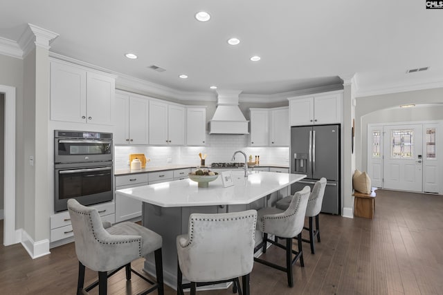 143 Club Ridge Rd, Elgin, SC 29045 - kitchen with appliances with stainless steel finishes, custom exhaust hood, a kitchen breakfast bar, a kitchen island with sink, and white cabinetry