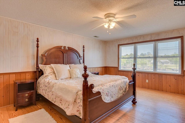 518 Pioneer Shores Rd, Prosperity, SC 29127 - bedroom with wooden walls, a textured ceiling, a wainscoted wall, light wood-style floors, and ceiling fan