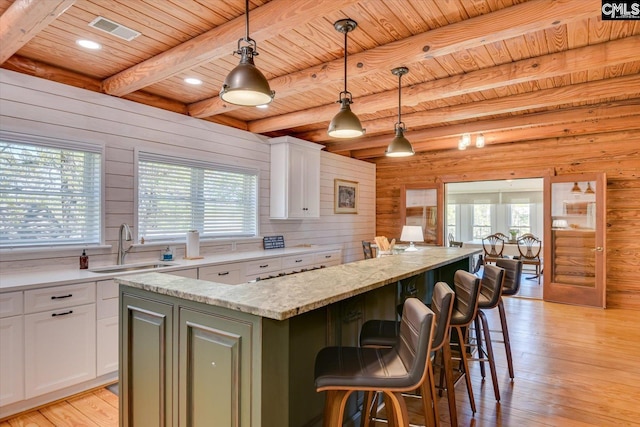 518 Pioneer Shores Rd, Prosperity, SC 29127 - kitchen featuring a center island, a wood ceiling with exposed beams, wood walls, white cabinetry, and light wood-style flooring