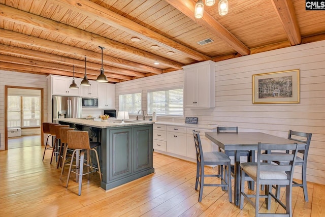 518 Pioneer Shores Rd, Prosperity, SC 29127 - kitchen featuring built in microwave, stainless steel fridge, a wooden ceiling with exposed beams, white cabinets, and wooden walls
