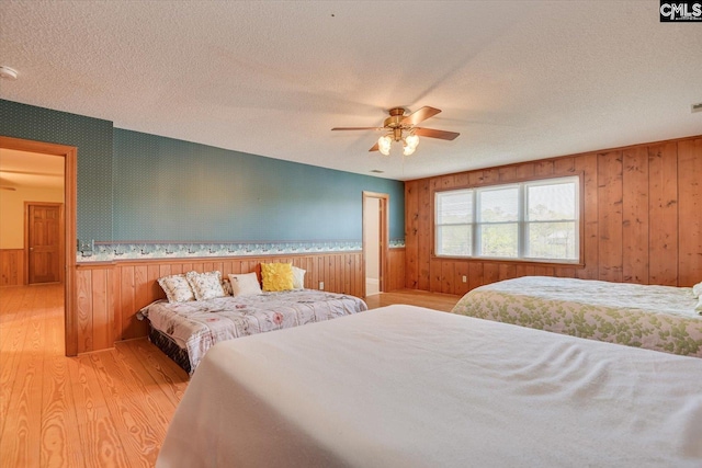 518 Pioneer Shores Rd, Prosperity, SC 29127 - bedroom with light wood-style floors, wood walls, wainscoting, a textured ceiling, and ceiling fan