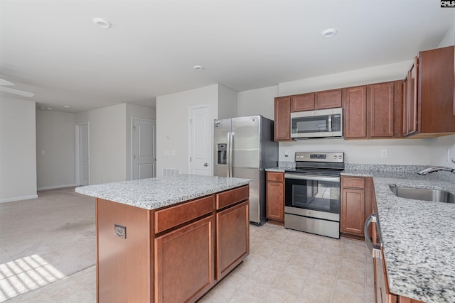 939 Sequoia Dr, Lexington, SC 29073 - kitchen featuring appliances with stainless steel finishes, a center island, light stone counters, open floor plan, and brown cabinets