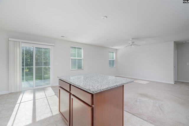 939 Sequoia Dr, Lexington, SC 29073 - kitchen featuring a kitchen island, light colored carpet, ceiling fan, light stone countertops, and open floor plan