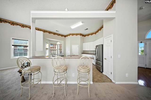 216 Founders Ridge Rd, Columbia, SC 29229 - kitchen featuring white cabinets, a breakfast bar area, light carpet, a peninsula, and freestanding refrigerator