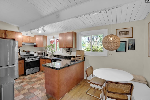 711 Sunset Dr, Columbia, SC 29203 - kitchen featuring appliances with stainless steel finishes, under cabinet range hood, a peninsula, brown cabinetry, and rail lighting