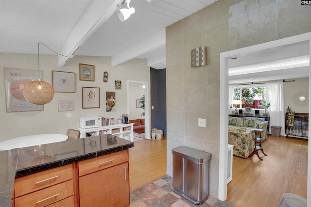 711 Sunset Dr, Columbia, SC 29203 - kitchen with dark countertops, white microwave, beamed ceiling, tile walls, and light wood-style flooring