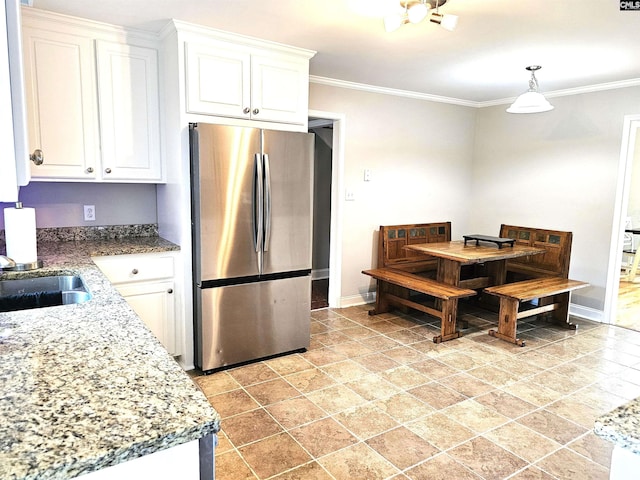 904 Sunnyhill Dr, Camden, SC 29020 - kitchen with freestanding refrigerator, white cabinets, crown molding, decorative light fixtures, and light stone counters
