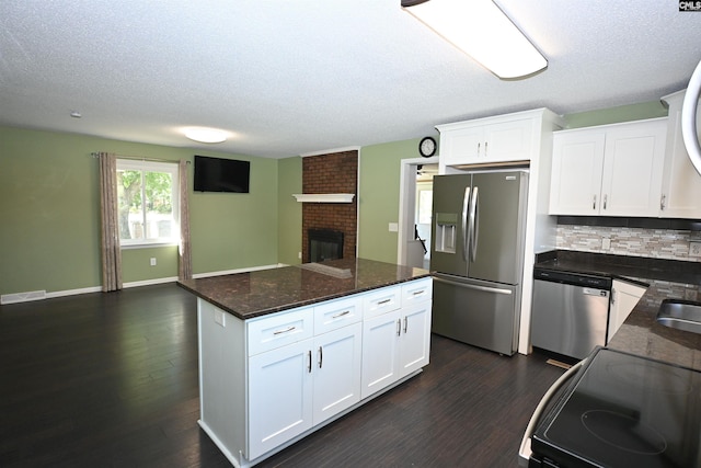 214 Mac St, Leesville, SC 29070 - kitchen with stainless steel appliances, a brick fireplace, a textured ceiling, dark wood-style flooring, and backsplash