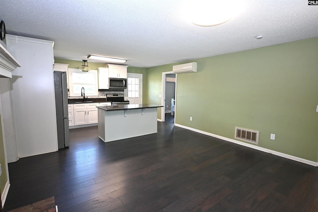 214 Mac St, Leesville, SC 29070 - kitchen featuring stainless steel appliances, dark countertops, a textured ceiling, dark wood-style flooring, and a center island
