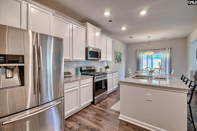 142 Summer Orchard Dr, Lexington, SC 29072 - kitchen featuring stainless steel appliances, dark wood-style floors, decorative backsplash, white cabinetry, and a center island with sink