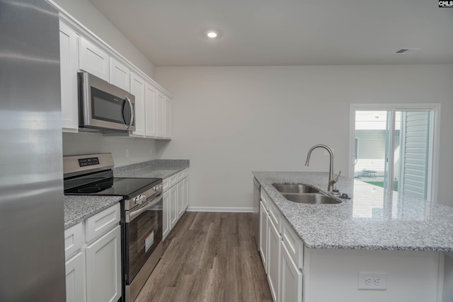 739 Wild Duck Ln, Columbia, SC 29203 - kitchen with stainless steel appliances, an island with sink, dark wood finished floors, white cabinetry, and light stone counters