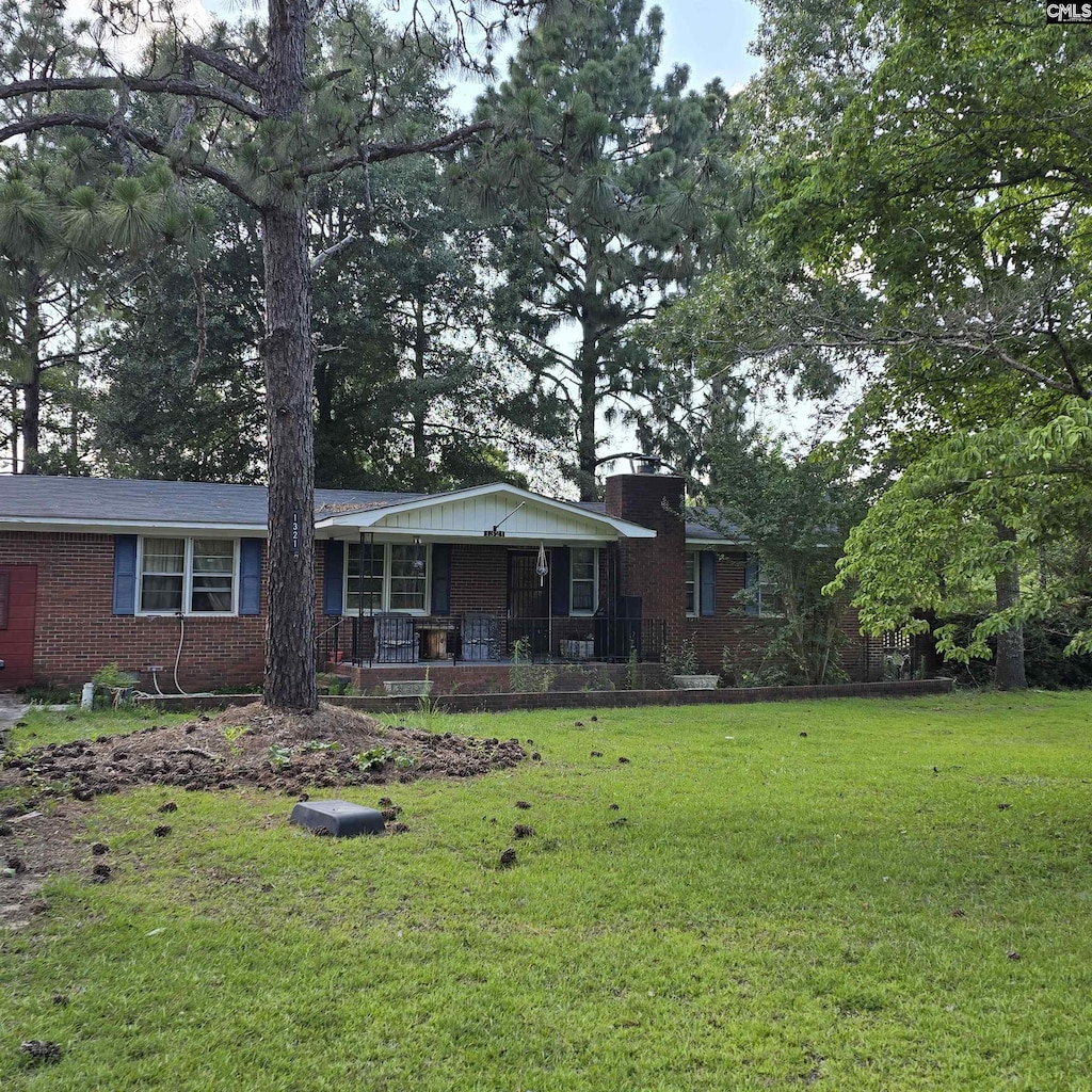 1321 Spring Creek Rd, Lugoff, SC 29078 - ranch-style house featuring a porch, brick siding, a front yard, and a chimney
