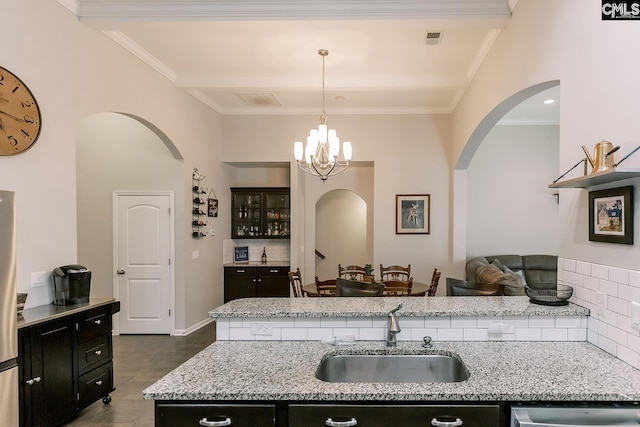 122 Azur Ave, Chapin, SC 29036 - kitchen featuring arched walkways, dark cabinets, tasteful backsplash, a chandelier, and light stone counters
