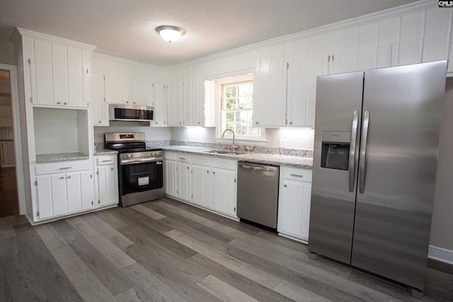 320 Perkins Ln, Camden, SC 29020 - kitchen featuring stainless steel appliances, ornamental molding, dark wood-style floors, white cabinetry, and light stone countertops