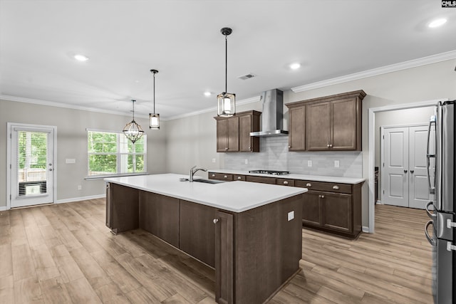 478 Harbour Pointe Dr, Columbia, SC 29229 - kitchen featuring wall chimney range hood, gas stovetop, freestanding refrigerator, light countertops, and a kitchen island with sink
